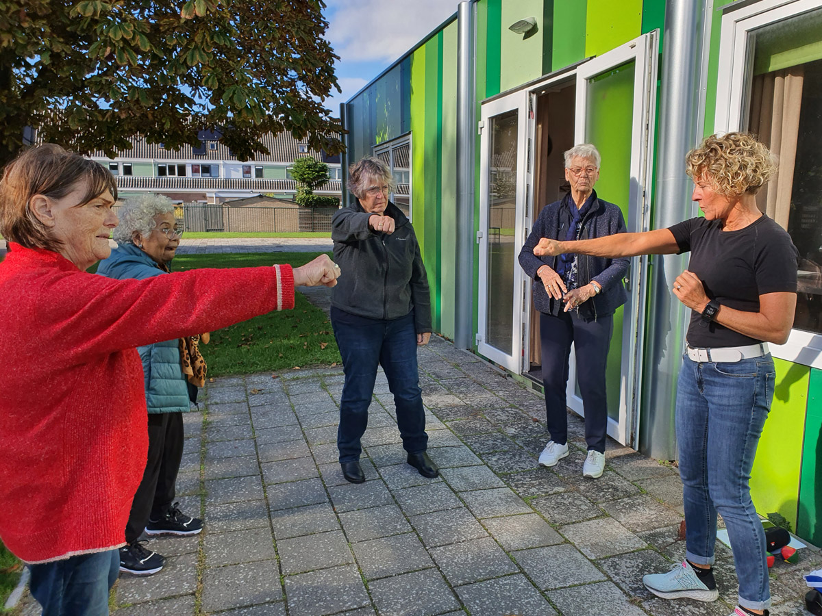 Bezoekers doen samen oefeningen buiten voor het Odensehuis